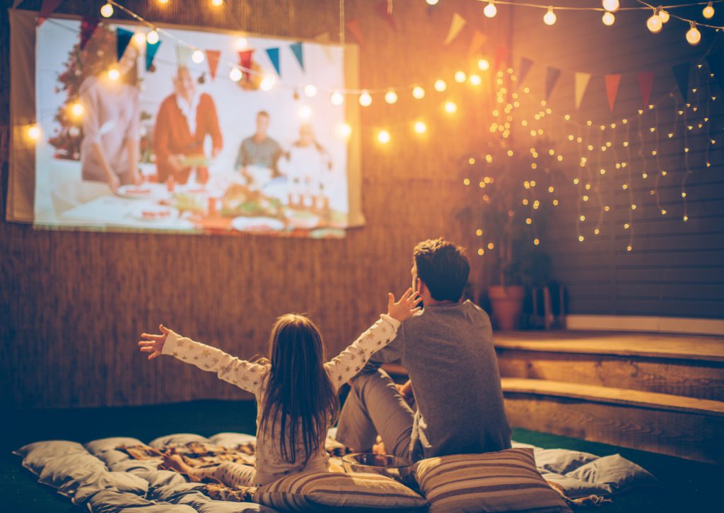 father and daughter watching a movie outside