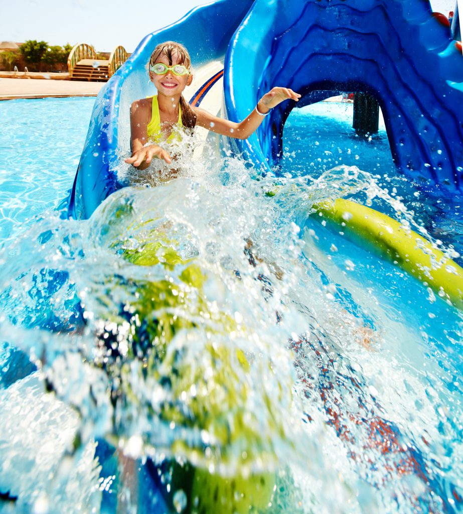 little girl on water slide at waterpark, water, wearing goggles,