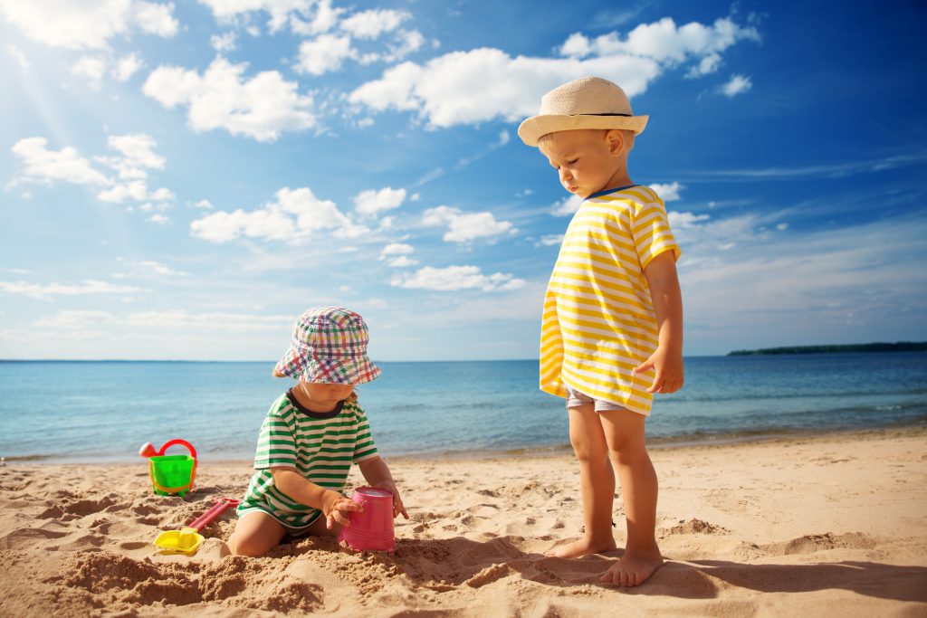 Boy and girl playing on the beach, Sand, Water, Blue sky, white clouds, beach pails, sand toys
