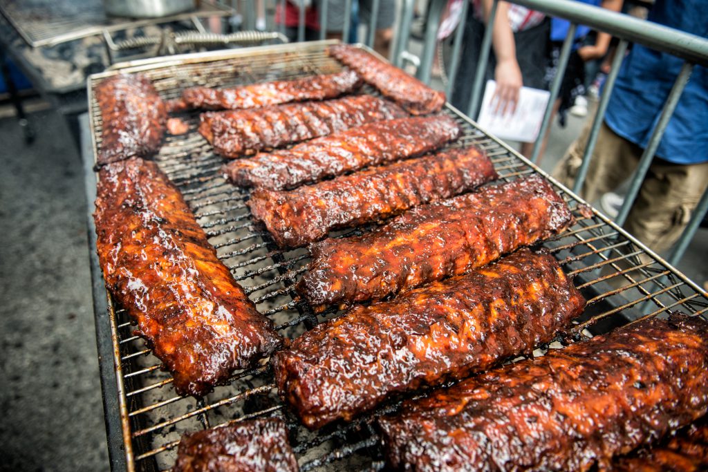 Pork Ribs street food Festival and BBQ, Glazed bbq ribs on a tray resting, ready with people in the background for judging and trying