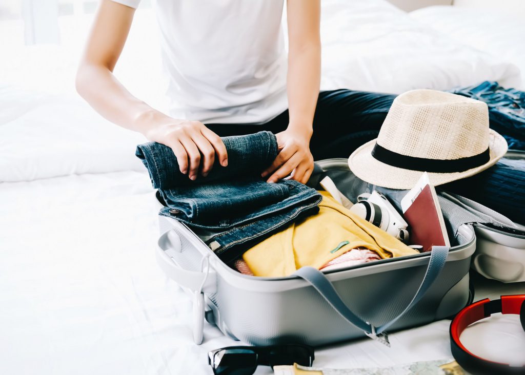 Woman packing suitcase with luggage for a beach trip