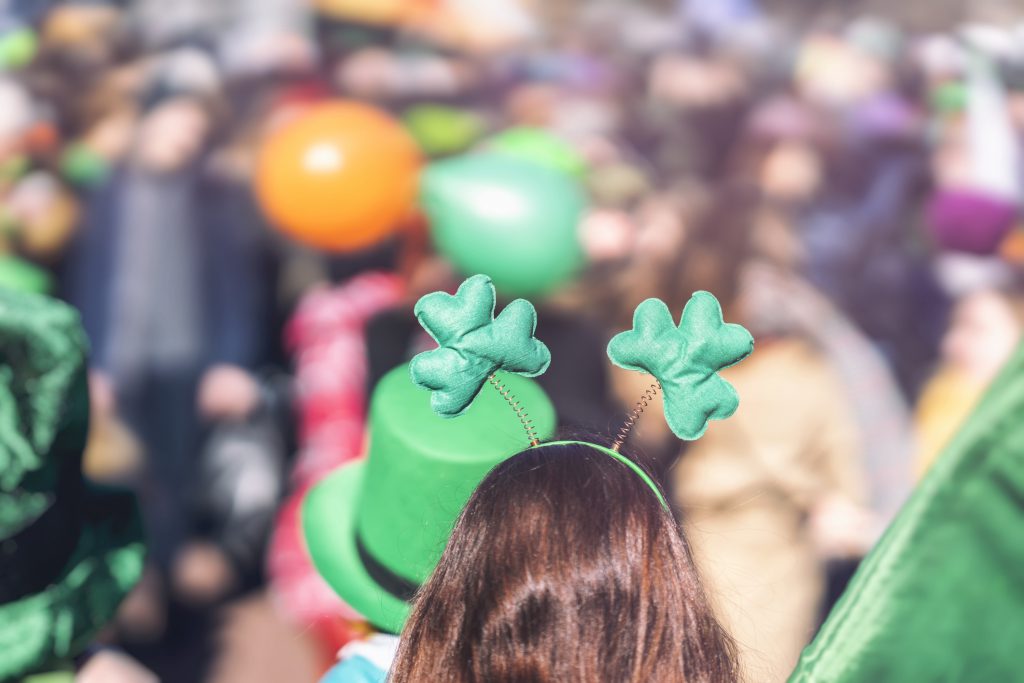 Clover head decoration on head of girl close-up. Saint Patricks day, parade in the city, selectriv focus, copy space